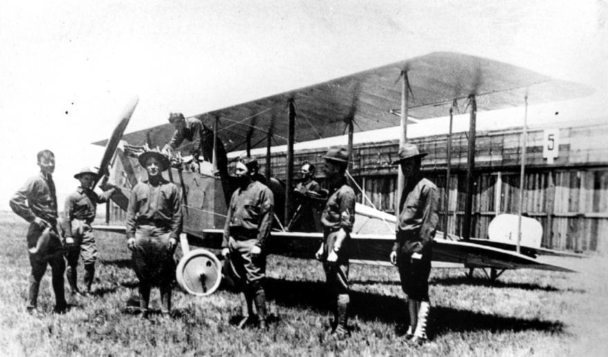 A group of men in front of an airplane.