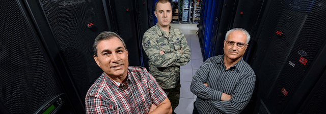 About AFTAC Link Button Image - 3 lab technicians posing in front of an array of computing and analytic equipment
