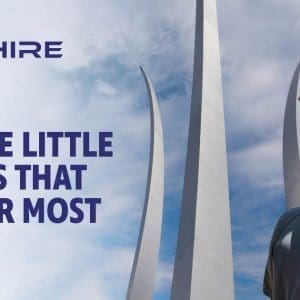 Aim Hire Episode 10: It's the Little Things that Matter Most. A Little boy sits on a man's shoulders, a three prong sculpture extends into the sky in the background.