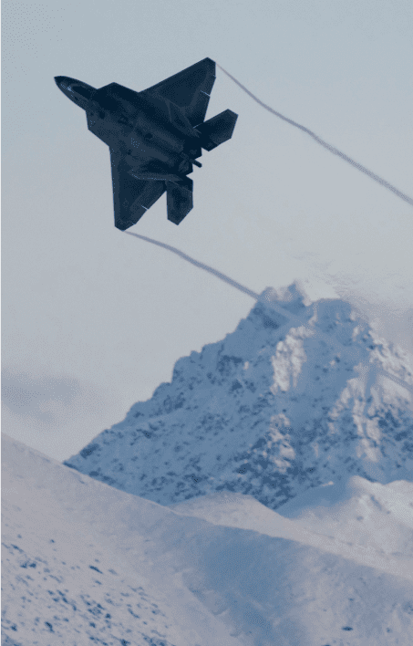 A jet flying with mountains in the background.